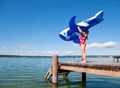 Girl holding inflatable whale on dock