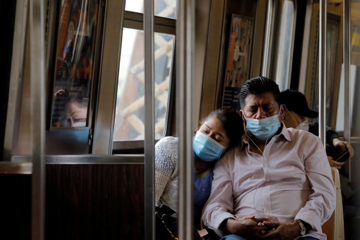 People in masks rest as they ride the subway during the outbreak of the coronavirus disease (COVID-19) in New York City