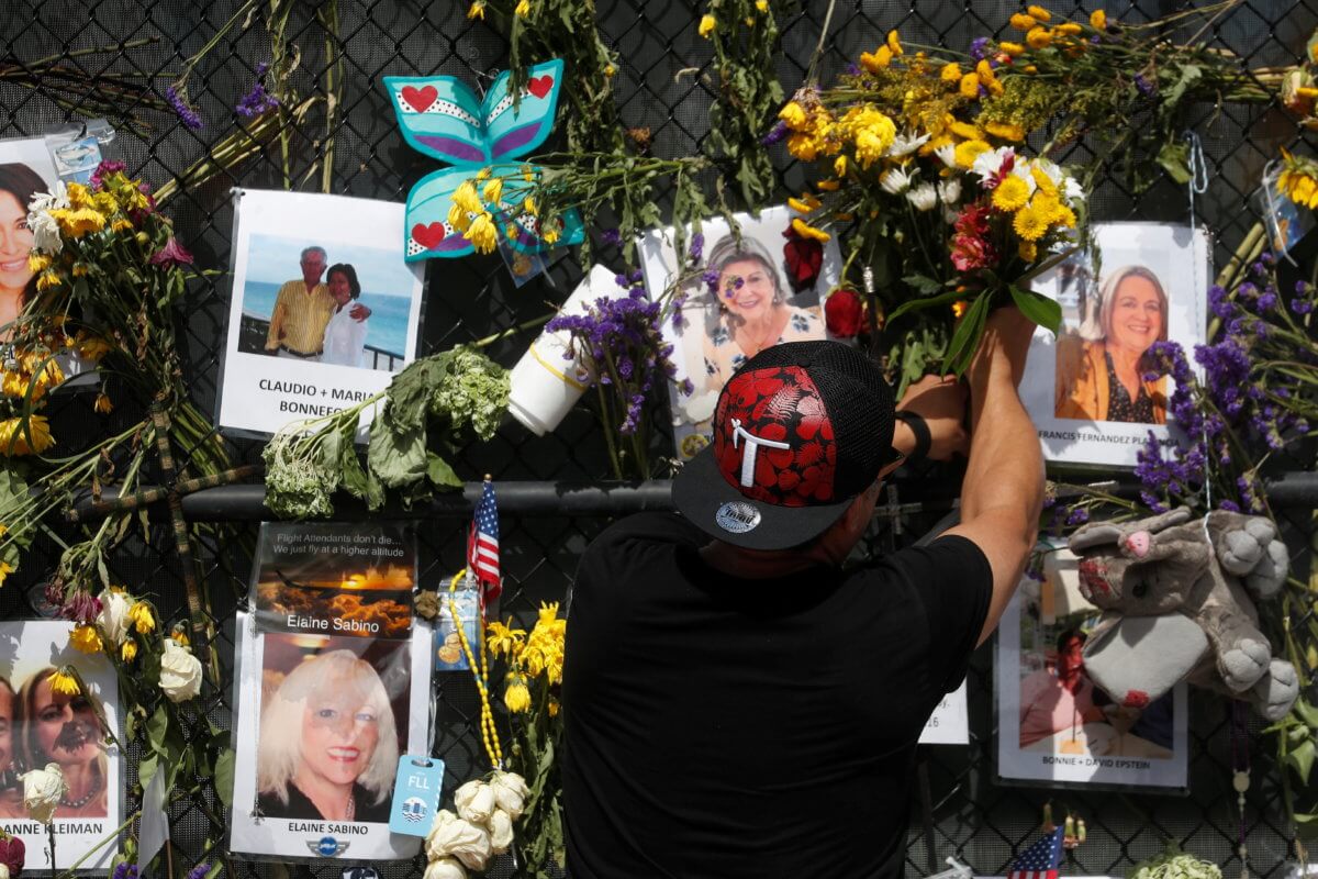 A man places flowers on a makeshift memorial for the victims of the Surfside’s Champlain Towers South condominium collapse in Miami, Florida