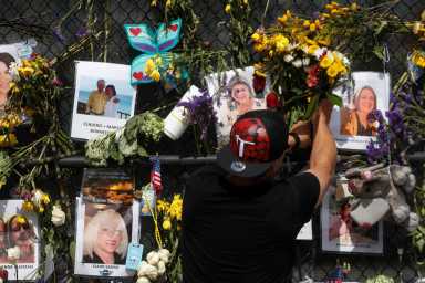 A man places flowers on a makeshift memorial for the victims of the Surfside’s Champlain Towers South condominium collapse in Miami, Florida