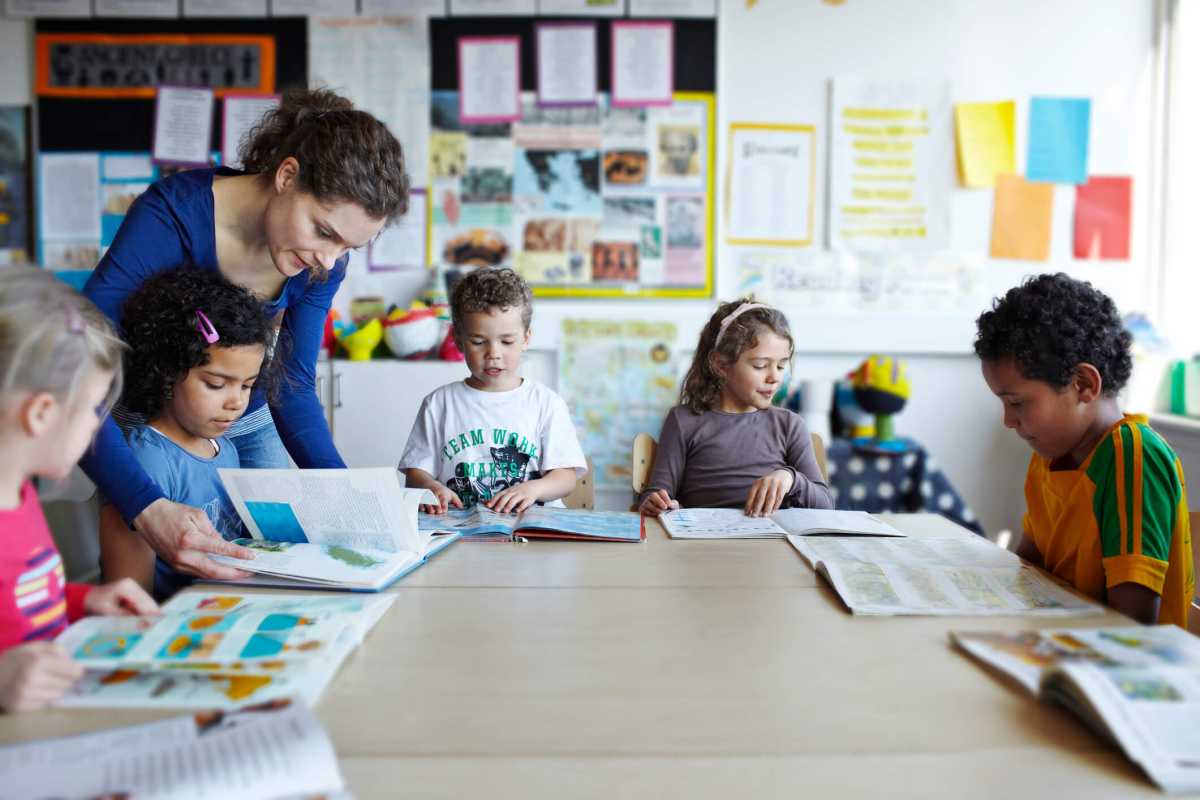 Teacher looking in books with children