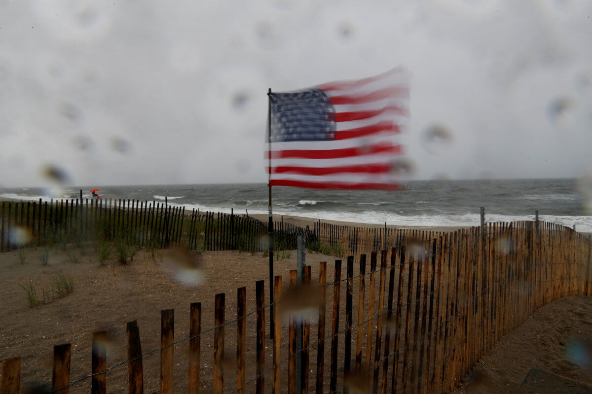 A U.S. flag blows in heavy wind at the beach, as Tropical Storm Fay was expected to sweep across the heavily populated northeastern United States, in the Rockaways section of the Queens borough of New York