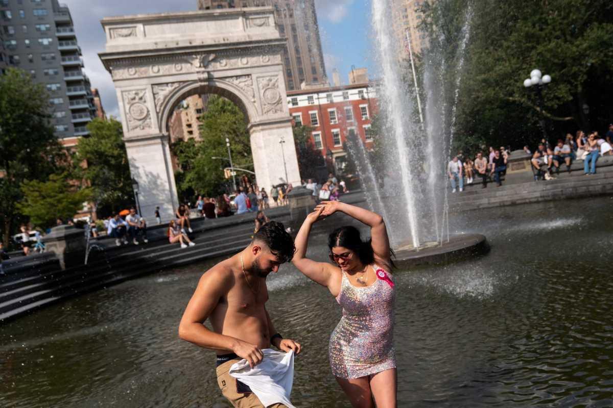 People cool off themselves on a fountain during a heat wave in New York City