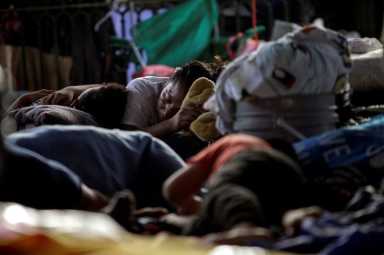 FILE PHOTO: Asylum-seeking migrants, who were apprehended and returned to Mexico under Title 42 after crossing the border from Mexico into the U.S., rest in a public square where hundreds of migrants live in tents, in Reynosa
