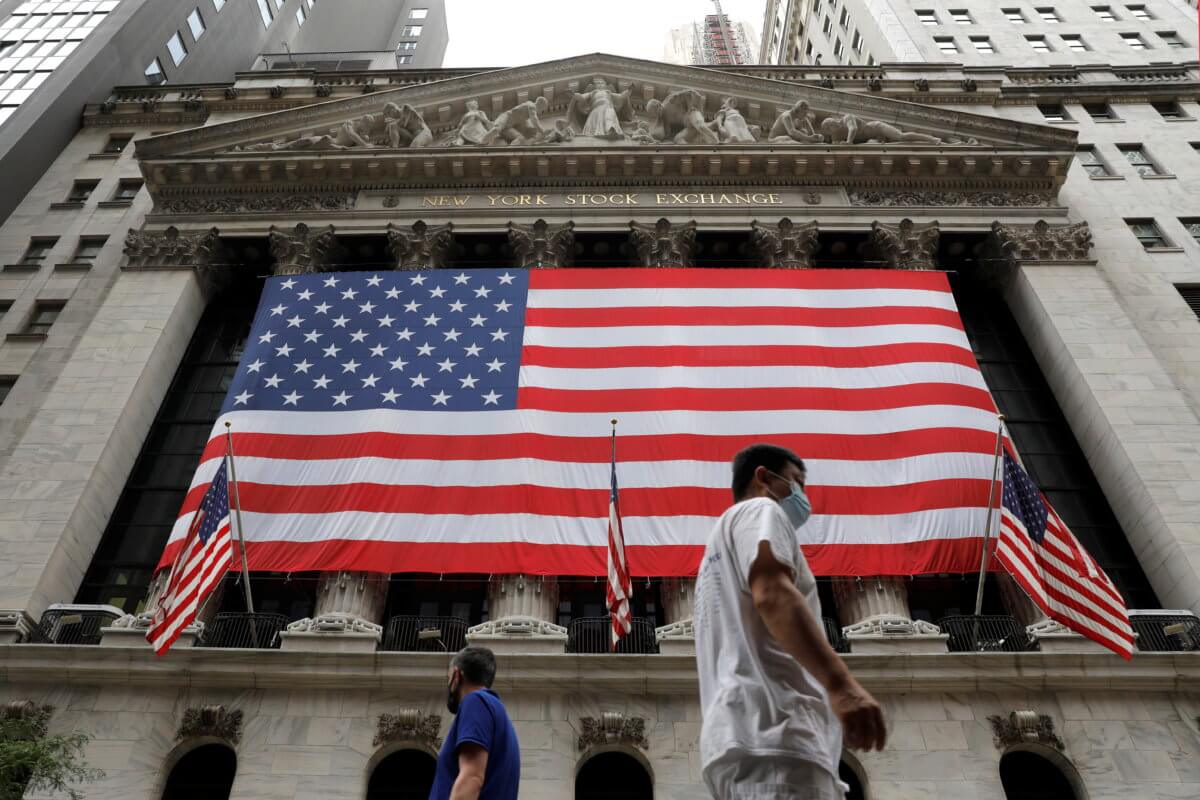 FILE PHOTO: People walk by the New York Stock Exchange (NYSE) in Manhattan, New York City
