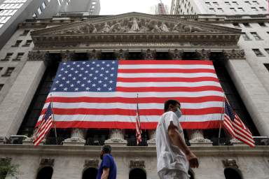 FILE PHOTO: People walk by the New York Stock Exchange (NYSE) in Manhattan, New York City