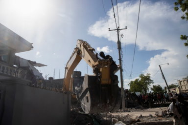 A heavy machine removes debris from a house after a 7.2 magnitude earthquake in Les Cayes