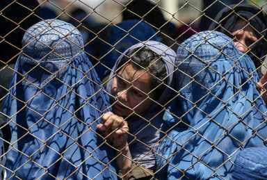 FILE PHOTO: Afghan women wait to receive free wheat donated by the Afghan government during a quarantine, amid concerns about the coronavirus disease (COVID-19) in Kabul