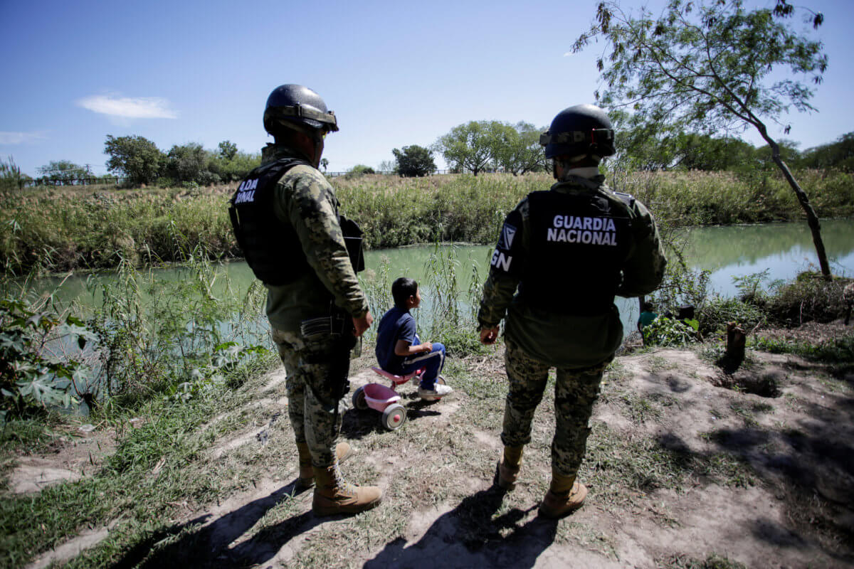 FILE PHOTO: A migrant boy, an asylum seeker sent back to Mexico from the U.S. under the “Remain in Mexico” program officially named Migrant Protection Protocols (MPP), is seen near two members of the Mexican National Guard at a provisional campsite near th