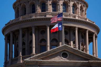 FILE PHOTO: The U.S flag and the Texas State flag fly over the Texas State Capitol in Austin