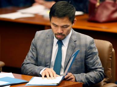 FILE PHOTO: Philippine Senator and boxing champion Manny Pacquiao reads his briefing materials as he prepares for the Senate session in Pasay city, Metro Manila