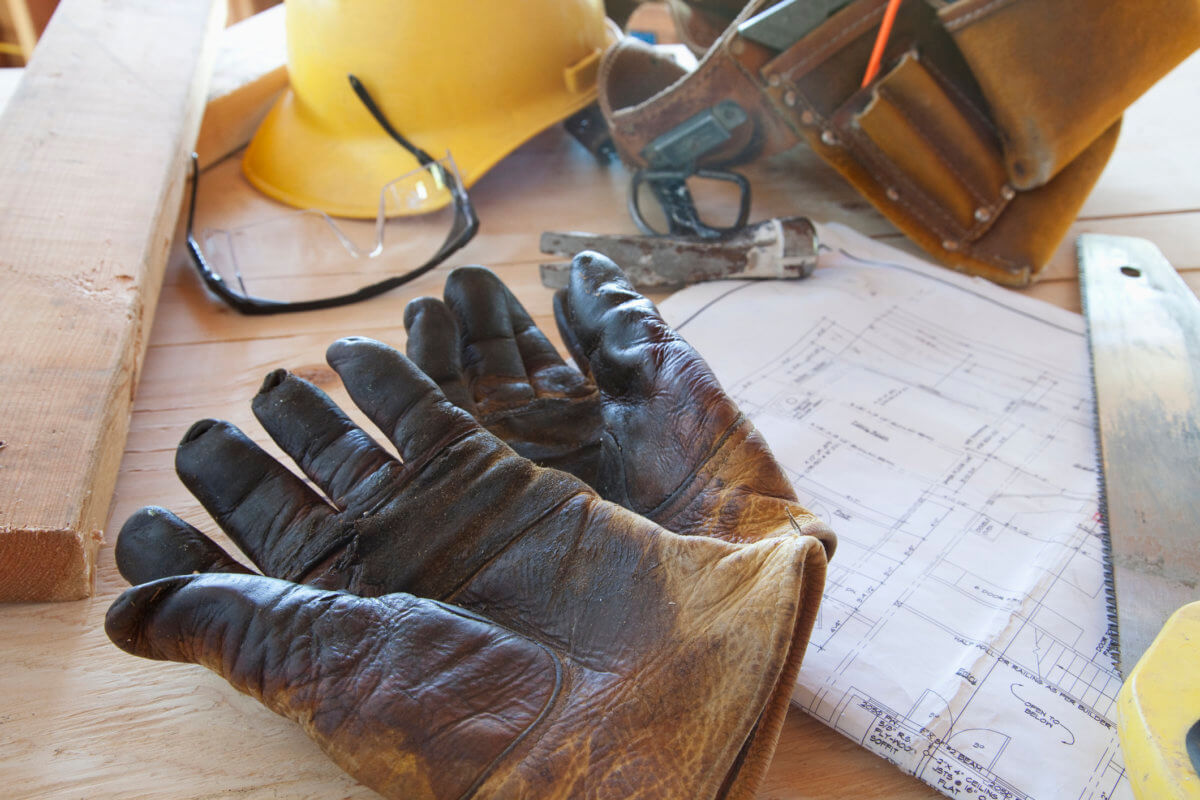 Gloves, blueprints, and tool belt on table