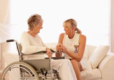 Older Caucasian woman in wheelchair talking with caregiver