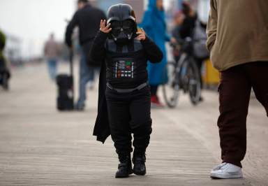 A child wearing a Darth Vader Halloween costume adjusts his face mask on the boardwalk before the arrival of Hurricane Sandy at Coney Island