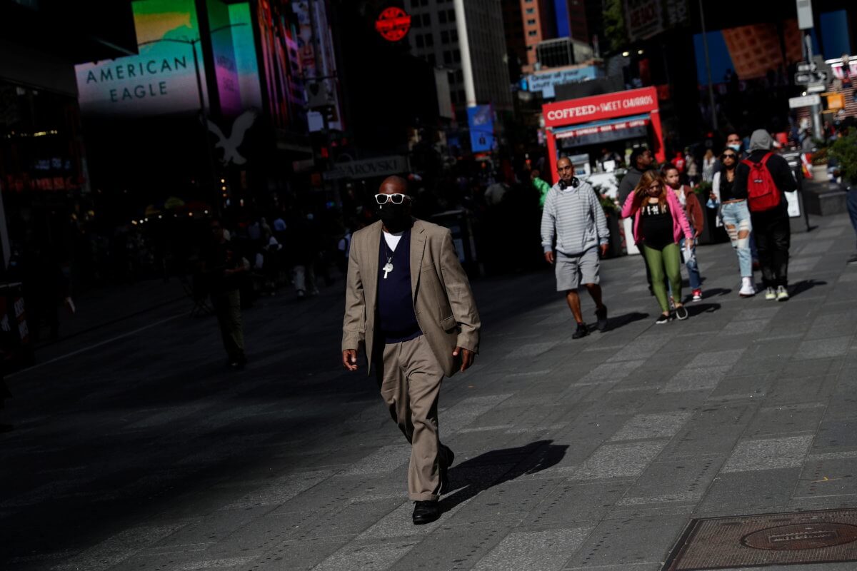 A man wearing a protective face mask walks, amid the coronavirus disease (COVID-19) pandemic, through the Times Square area in the Midtown Manhattan section of New York City