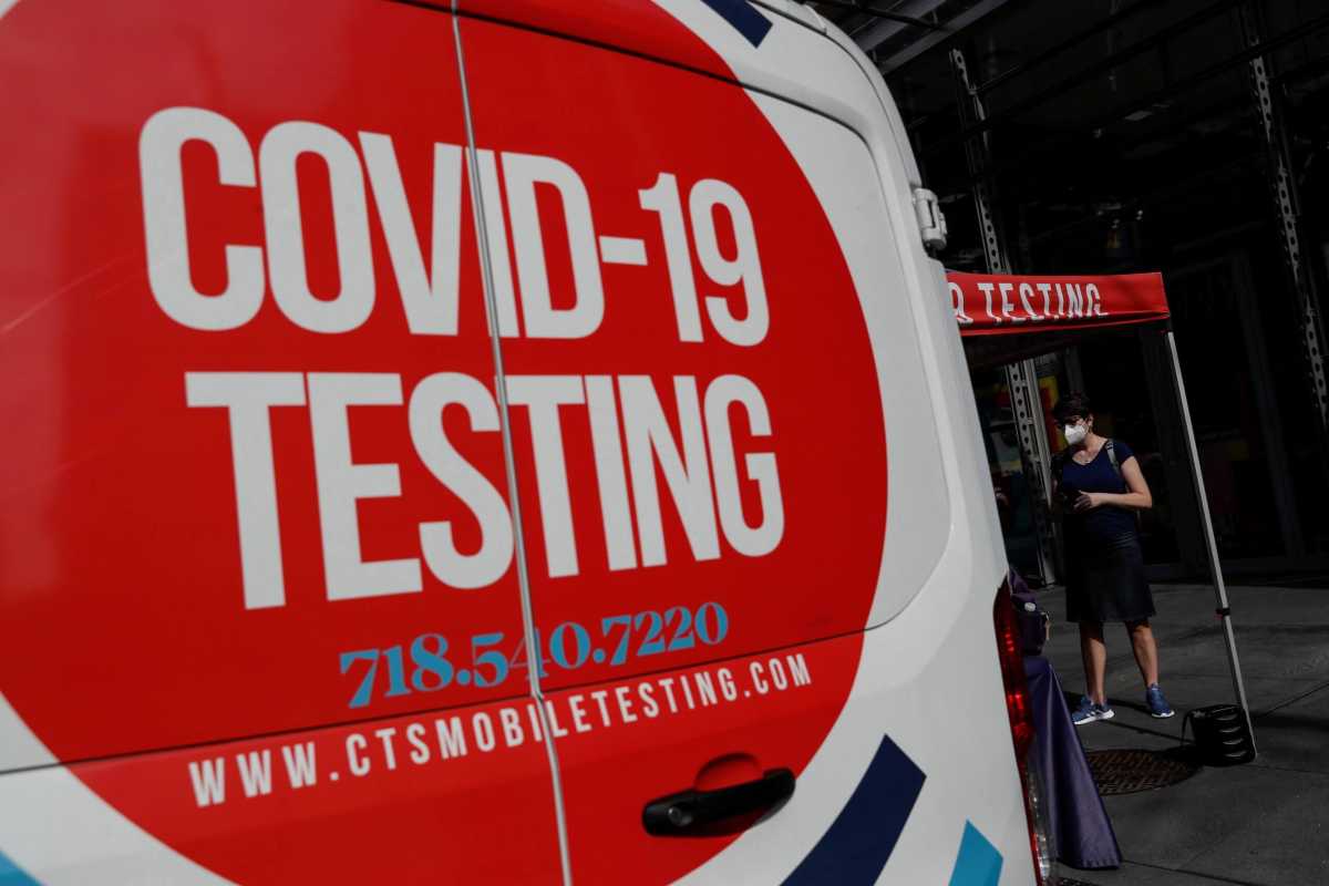 FILE PHOTO: A woman wearing a protective face mask waits at a coronavirus disease (COVID-19) mobile testing site amid the pandemic in the Midtown Manhattan area of New York City