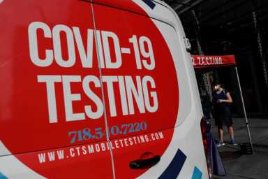 FILE PHOTO: A woman wearing a protective face mask waits at a coronavirus disease (COVID-19) mobile testing site amid the pandemic in the Midtown Manhattan area of New York City