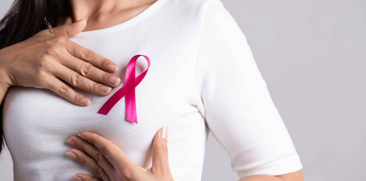 Closeup of pink badge ribbon on woman chest to support breast cancer cause. Healthcare, medicine and breast cancer awareness.