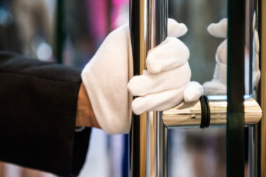 Doorman with White Gloves Opening Door at Luxury Shopping Mall