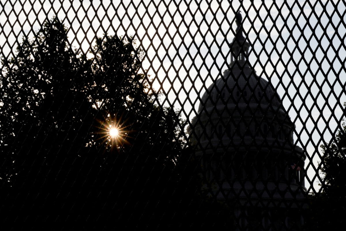 FILE PHOTO: The sun rises behind the U.S. Capitol, surrounded by a security fence ahead of an expected rally Saturday in support of the Jan. 6 defendants in Washington