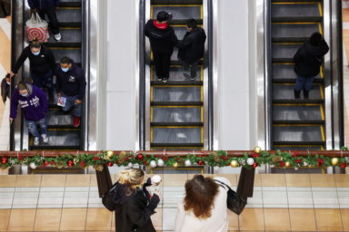 People ride an escalator while others stand at a mall during holiday season shopping as the Omicron coronavirus variant continues to spread in Brooklyn