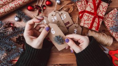Women’s hands make Christmas advent calendar a wooden background.