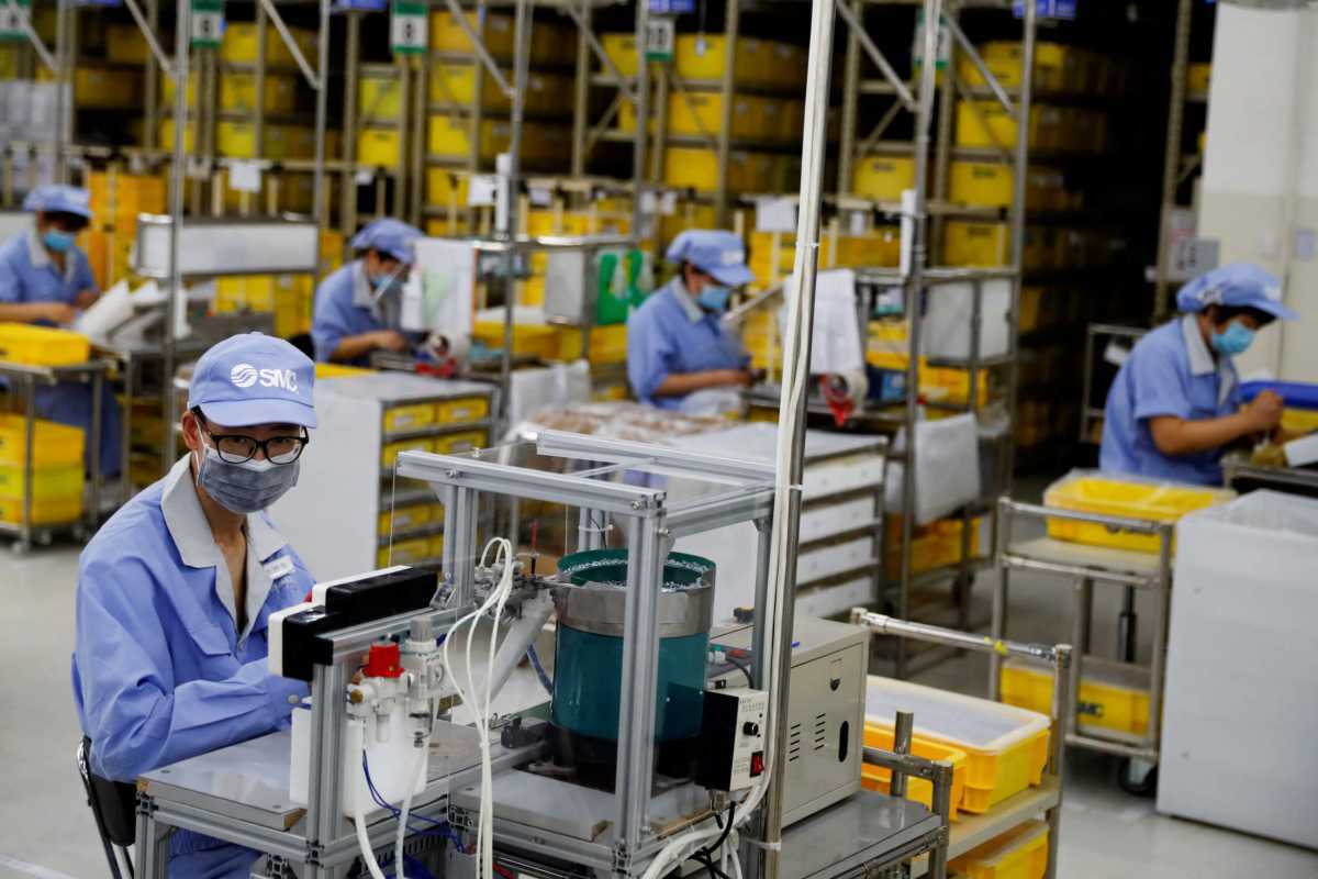FILE PHOTO: Employees wearing face masks work at a factory of the component maker SMC during a government organised tour of its facility following the outbreak of the coronavirus disease (COVID-19), in Beijing, China