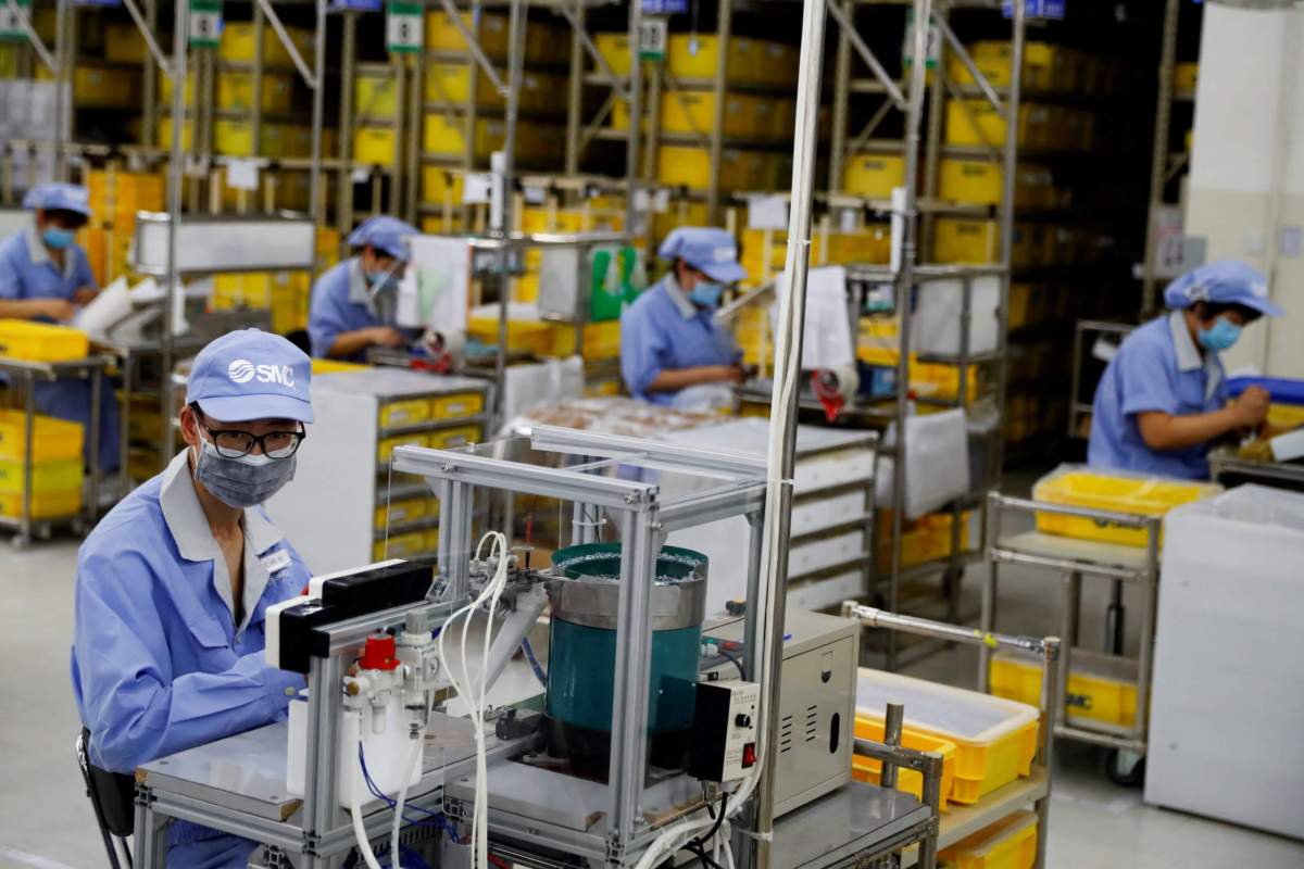 FILE PHOTO: Employees wearing face masks work at a factory of the component maker SMC during a government organised tour of its facility following the outbreak of the coronavirus disease (COVID-19), in Beijing, China