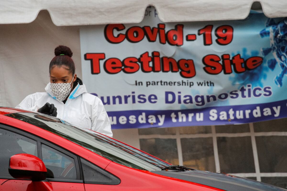 A healthcare worker takes a swab from a person sitting in a car at a drive-thru COVID-19 test center, during a surge in the coronavirus disease (COVID-19) infections in Newark, New Jersey