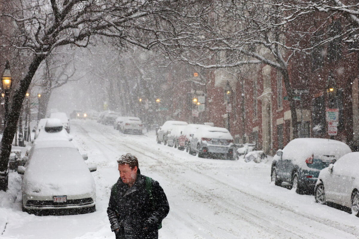 A pedestrian walks through falling snow during a winter storm in Boston
