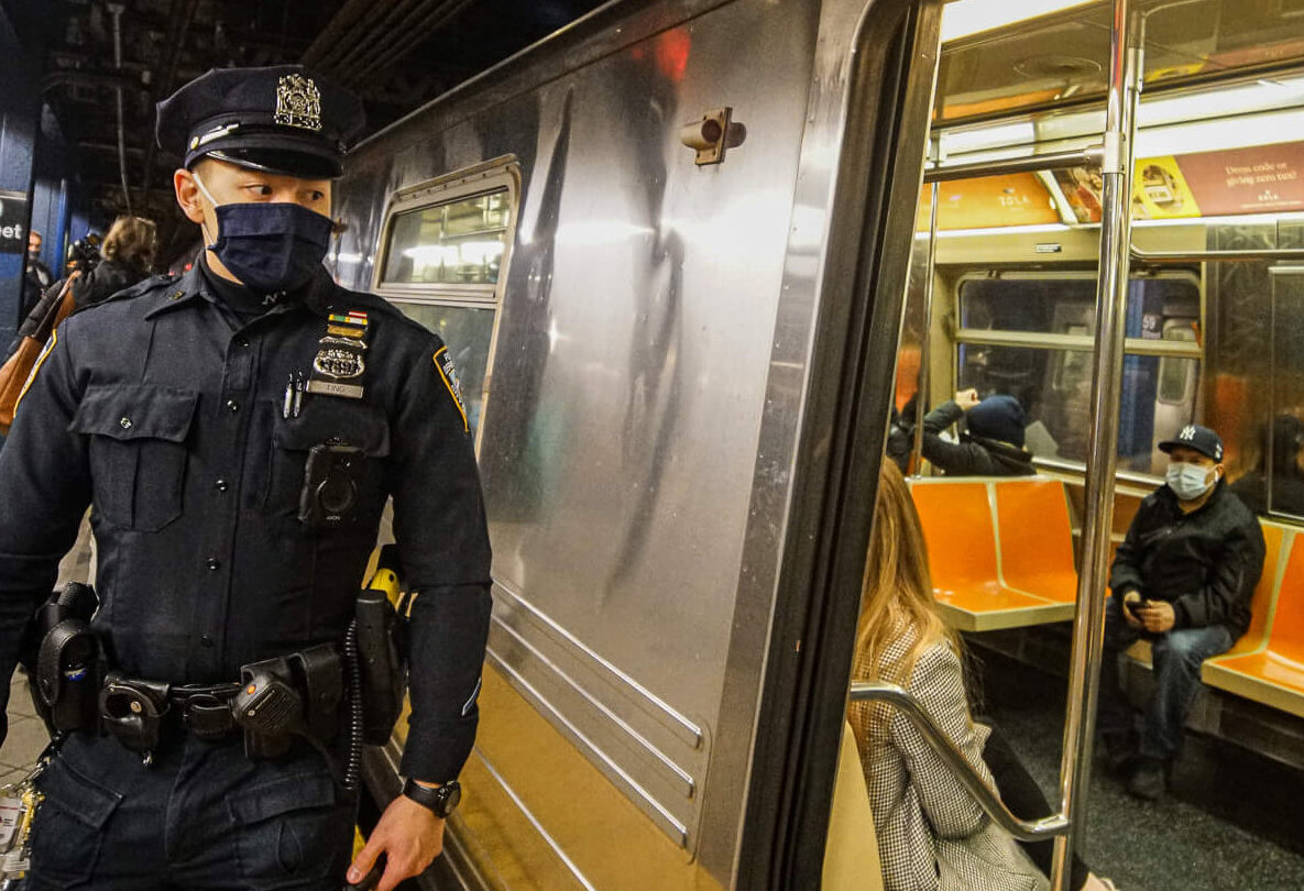An NYPD officer walks along the subway platform checking on straphangers