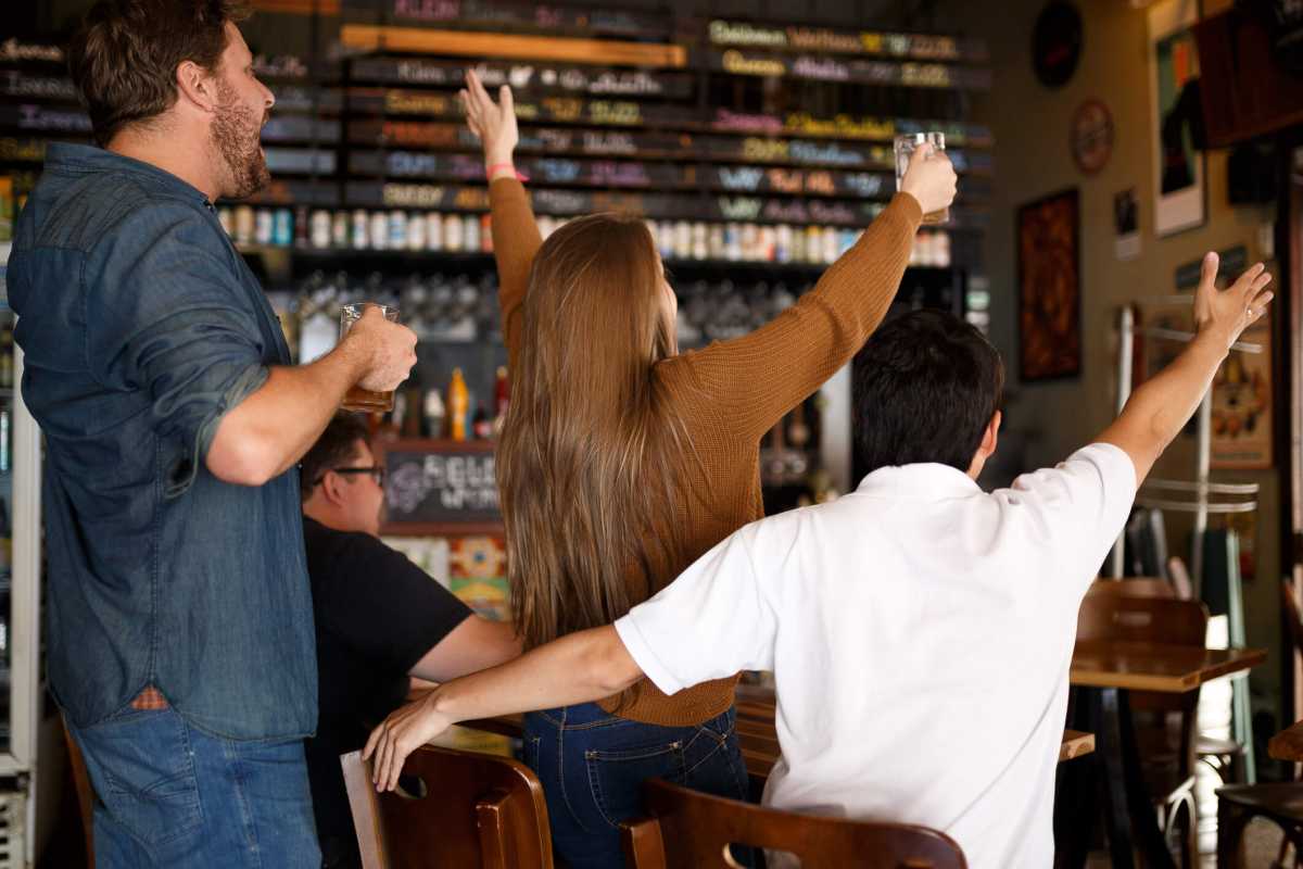 Friends watching sports on TV and drinking beer at the pub