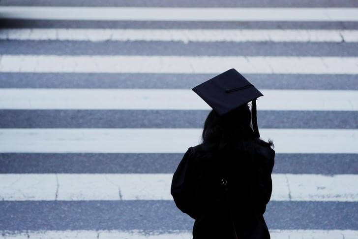 FILE PHOTO: A graduating student waits to cross the street in Cambridge, Massachusetts