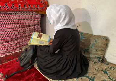 An Afghan schoolgirl reads from her book inside a house in Kabul