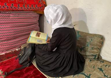 An Afghan schoolgirl reads from her book inside a house in Kabul