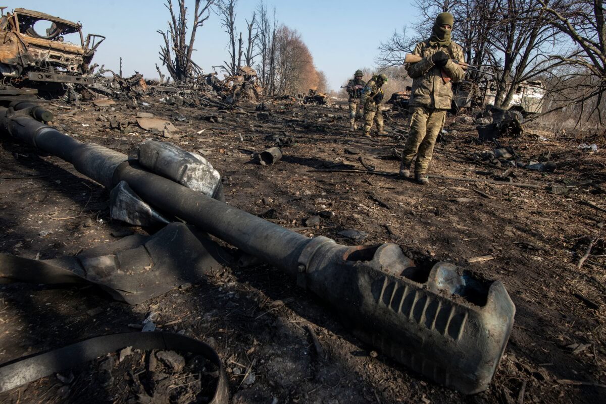 Ukrainian service members inspect destroyed Russian military vehicles near the town of Trostianets