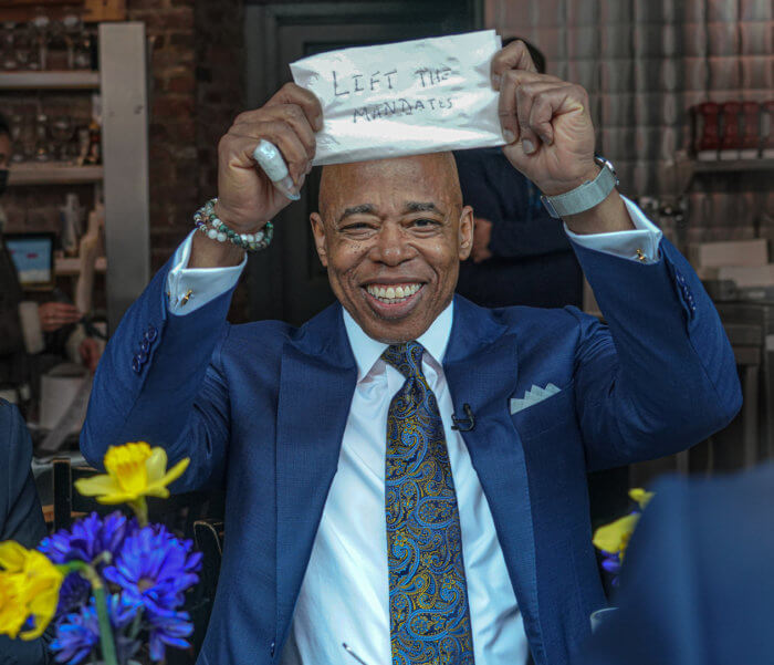 Mayor Eric Adams lifts a napkin with the words "Lift the mandates," while dining in the East Village on March 7.