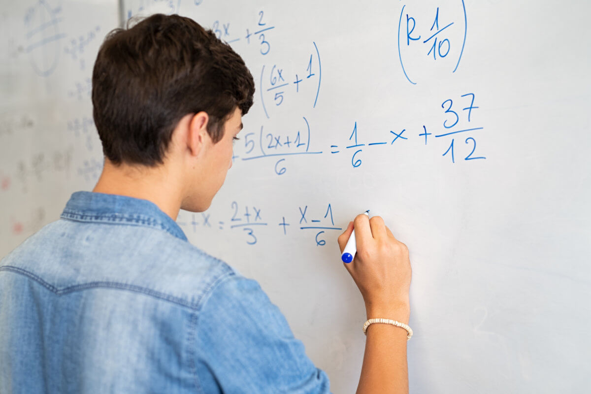 College student solving math equation on white board