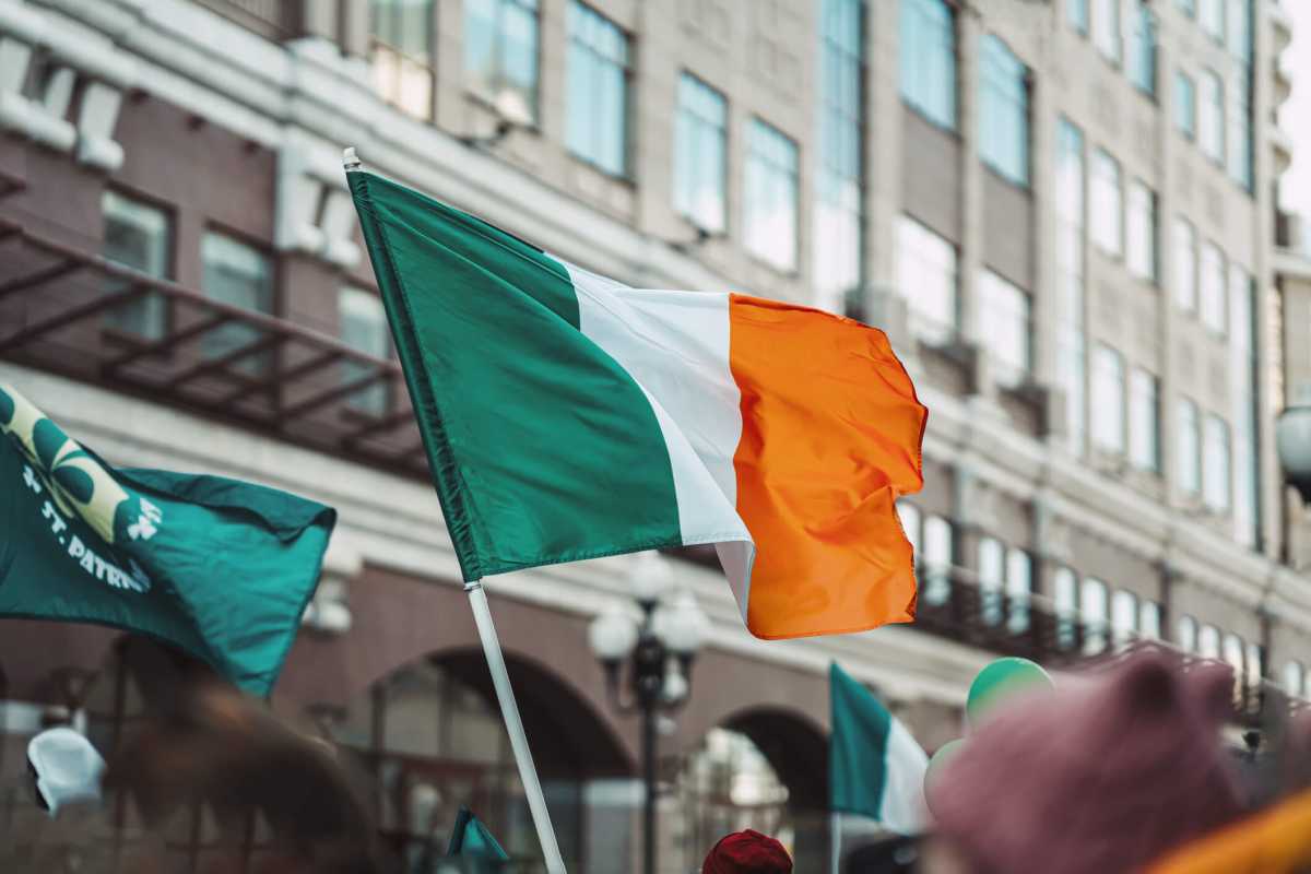 National Flag of Ireland close-up above people crowd, traditional carnival of St. Patrick’s Day
