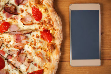 Fresh Italian pizza and smartphone on table