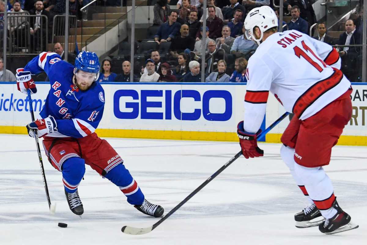 Rangers left wing Alexis Lafrenière attempts a move around Carolina Hurricanes center Jordan Staal.