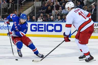 Rangers left wing Alexis Lafrenière attempts a move around Carolina Hurricanes center Jordan Staal.