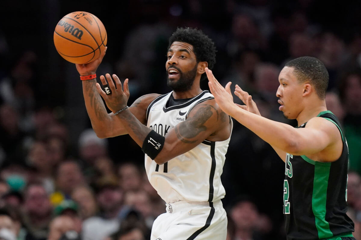 Brooklyn Nets guard Kyrie Irving passes the ball under pressure from Boston Celtics forward Grant Williams.