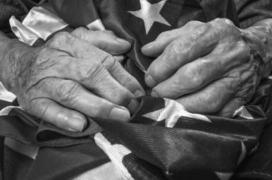 Old woman’s hands holding an American flag.