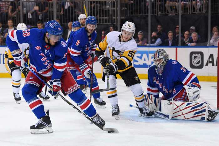 Rangers center Andrew Copp attempts to clear the puck out in front of the net.