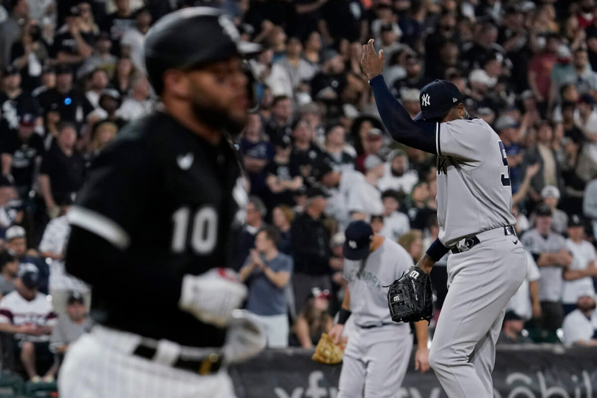 Yankees relief pitcher Aroldis Chapman, right, wipes his face as White Sox's Yoan Moncada heads to first base during the 9th inning