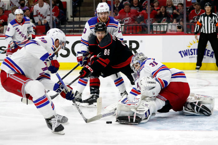 Hurricanes' Teuvo Teravainen drives the puck between Rangers' Adam Fox and Andrew Copp.
