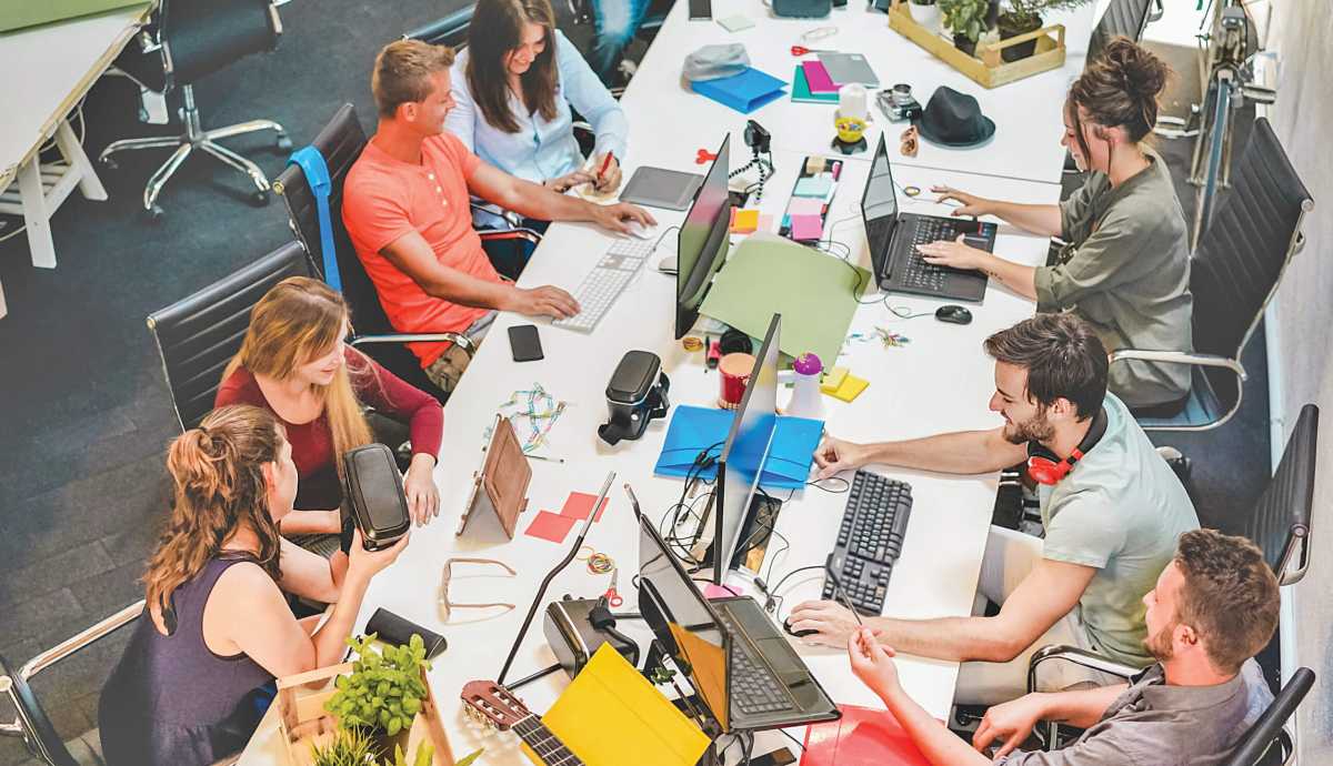 Young co-workers team talking during startup – Happy people planning a new project in creative workplace office – Technology, entrepreneur, marketing and concept – Focus on left man with headphones
