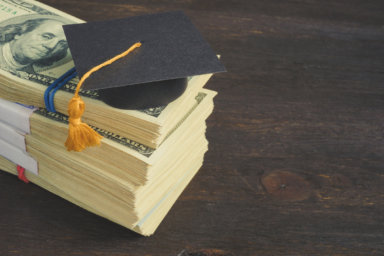 Savings for education and university concept. Stack of cash and graduation cap.