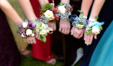 Girls holding arms out with corsage flowers for prom high school dance romance fun night party selective focus blur